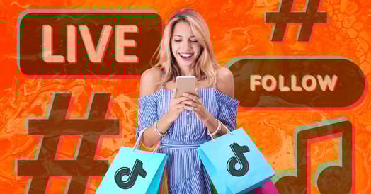 A blonde woman in a blue dress holding two shopping bags with the TikTok logo on the front smiling at her cellphone.
